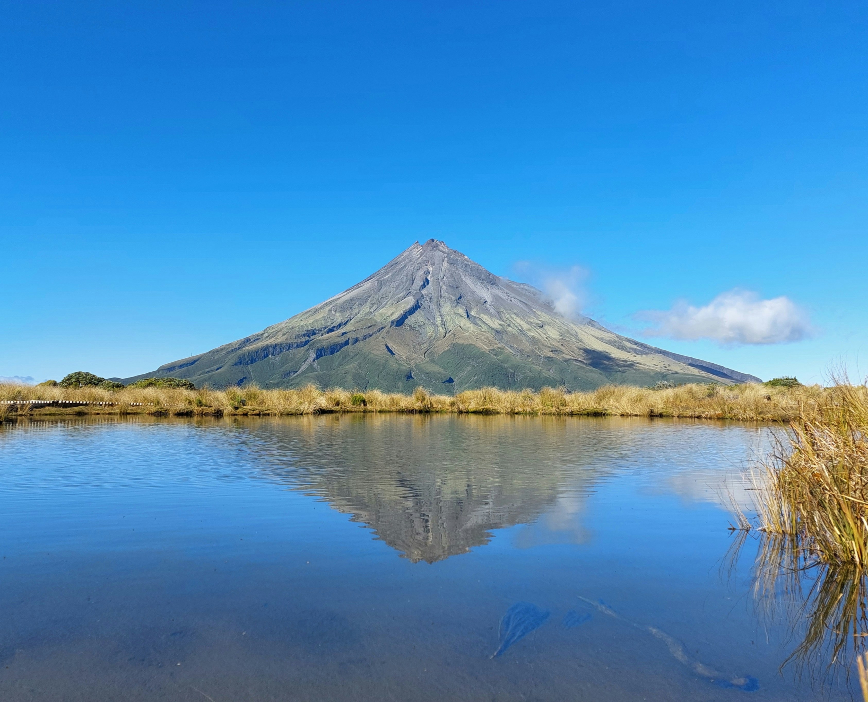 A symmetrical mountain peak mirrored in the still water of an alpine tarn
